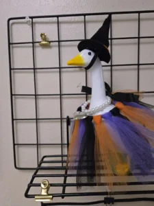A cement goose dressed as a Halloween witch, wearing a pointed black hat