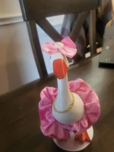 A tabletop goose wearing a delicate pink silk outfit