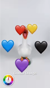 A white toy goose facing forward with its mouth open, surrounded by red, yellow, blue, black, and purple heart emojis